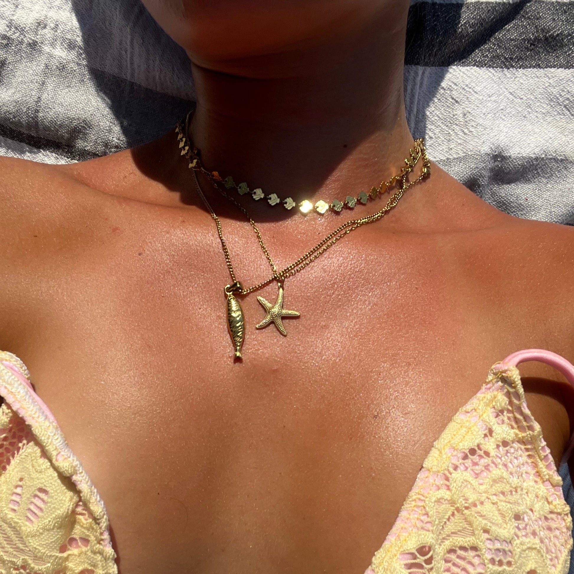 Close-up of a person wearing a pink lace bikini top with starfish jewelry.