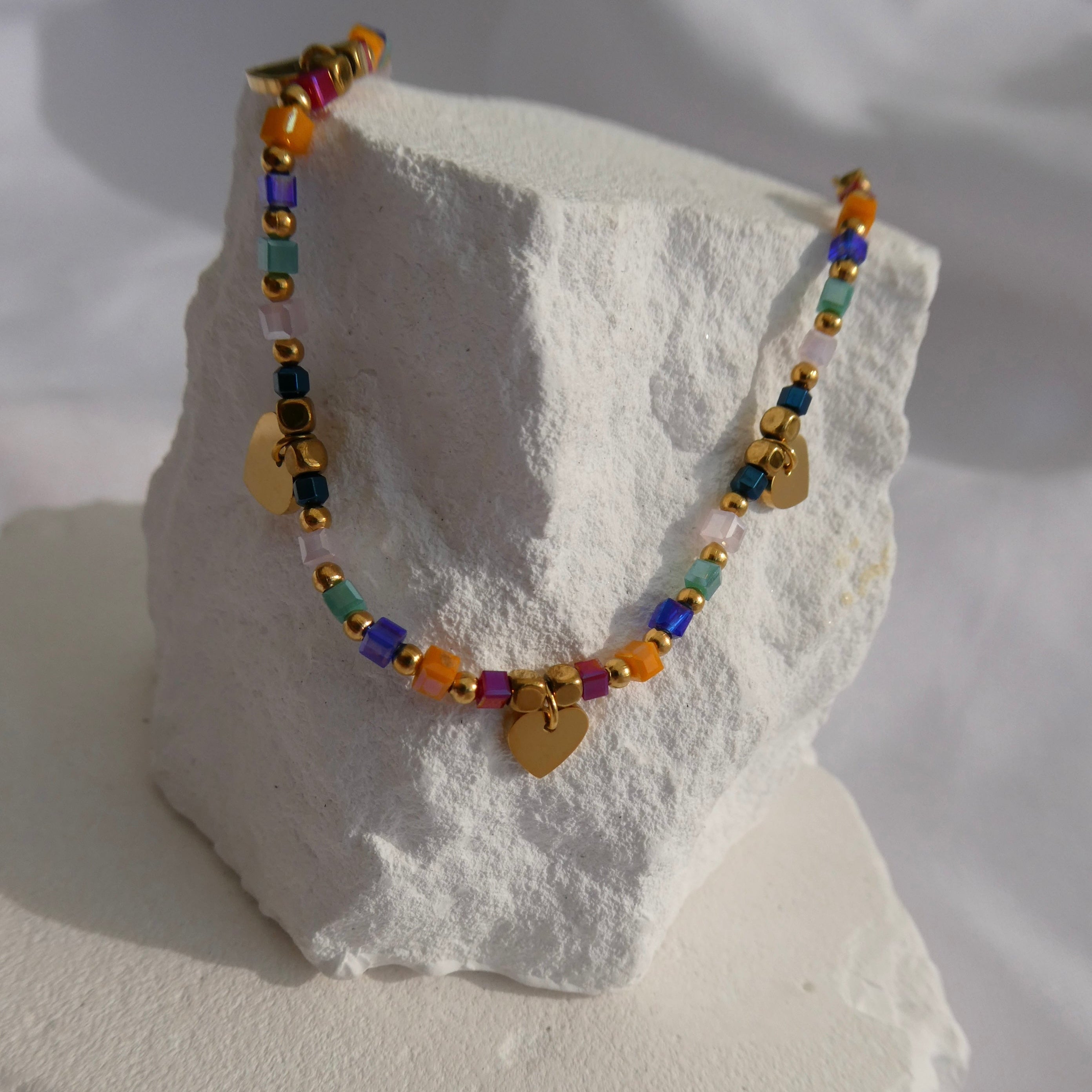 Colorful beaded necklace with gold accents on a white stone surface