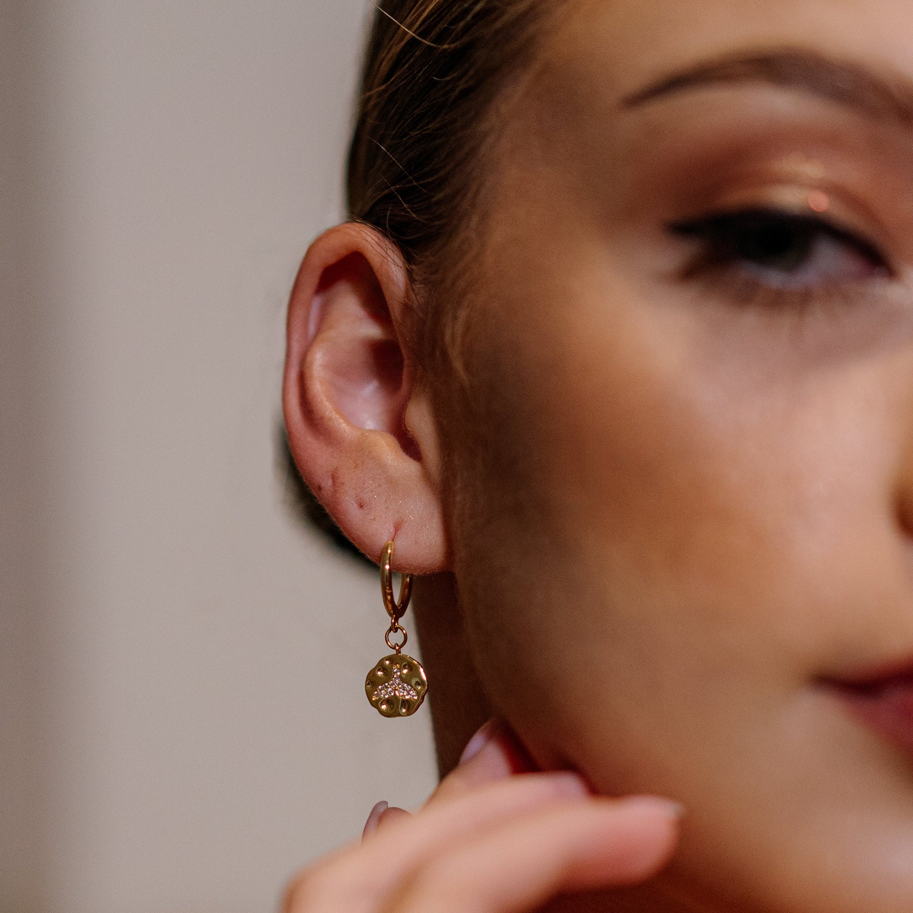 Close-up of a woman wearing a gold whale tale earring 