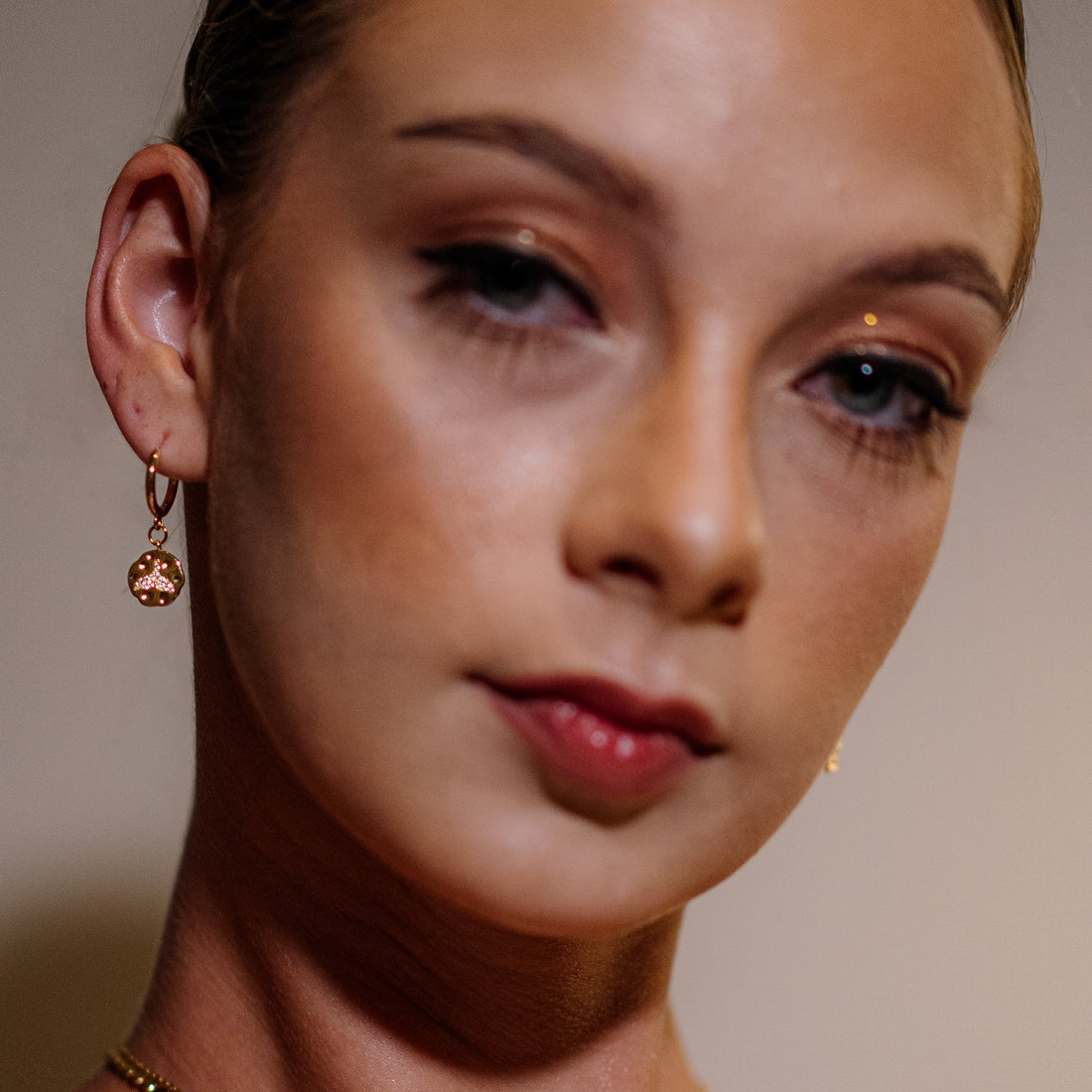 Close-up of a woman wearing gold whale tale earrings named Keiko