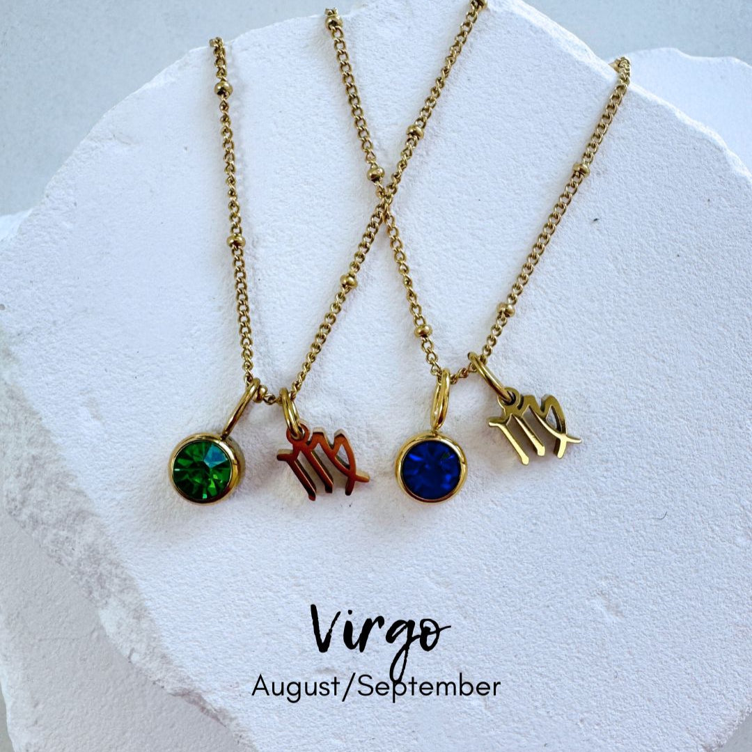 Two gold necklaces with zodiac symbols on a white stone surface, labeled 'Virgo' and 'August/September'.